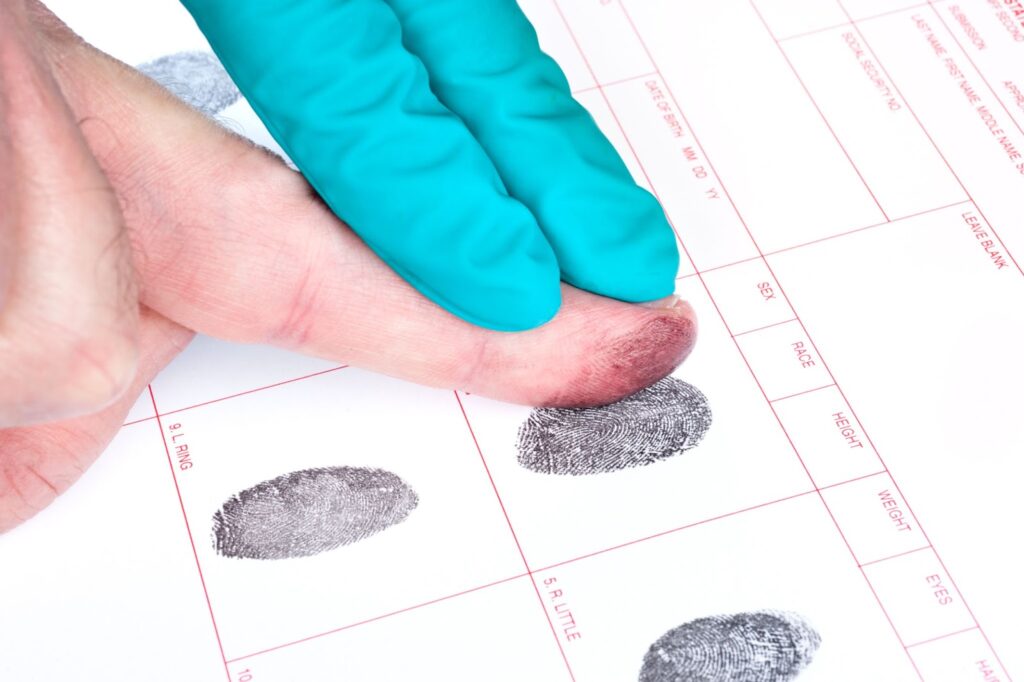 A closeup of a man’s finger being fingerprinted.