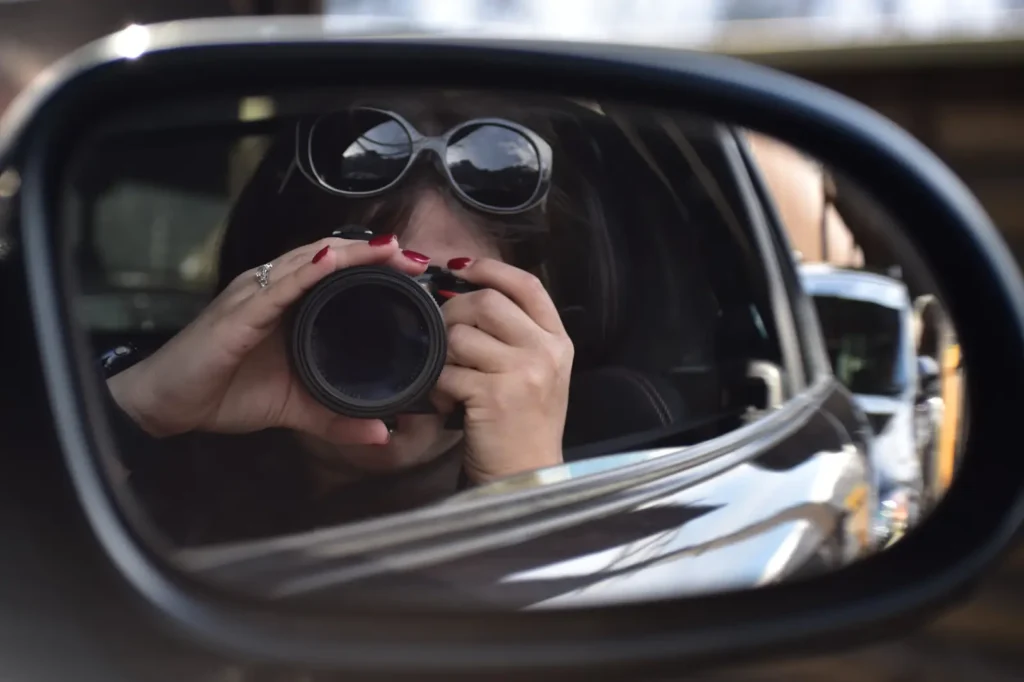 A woman taking a picture from her car.