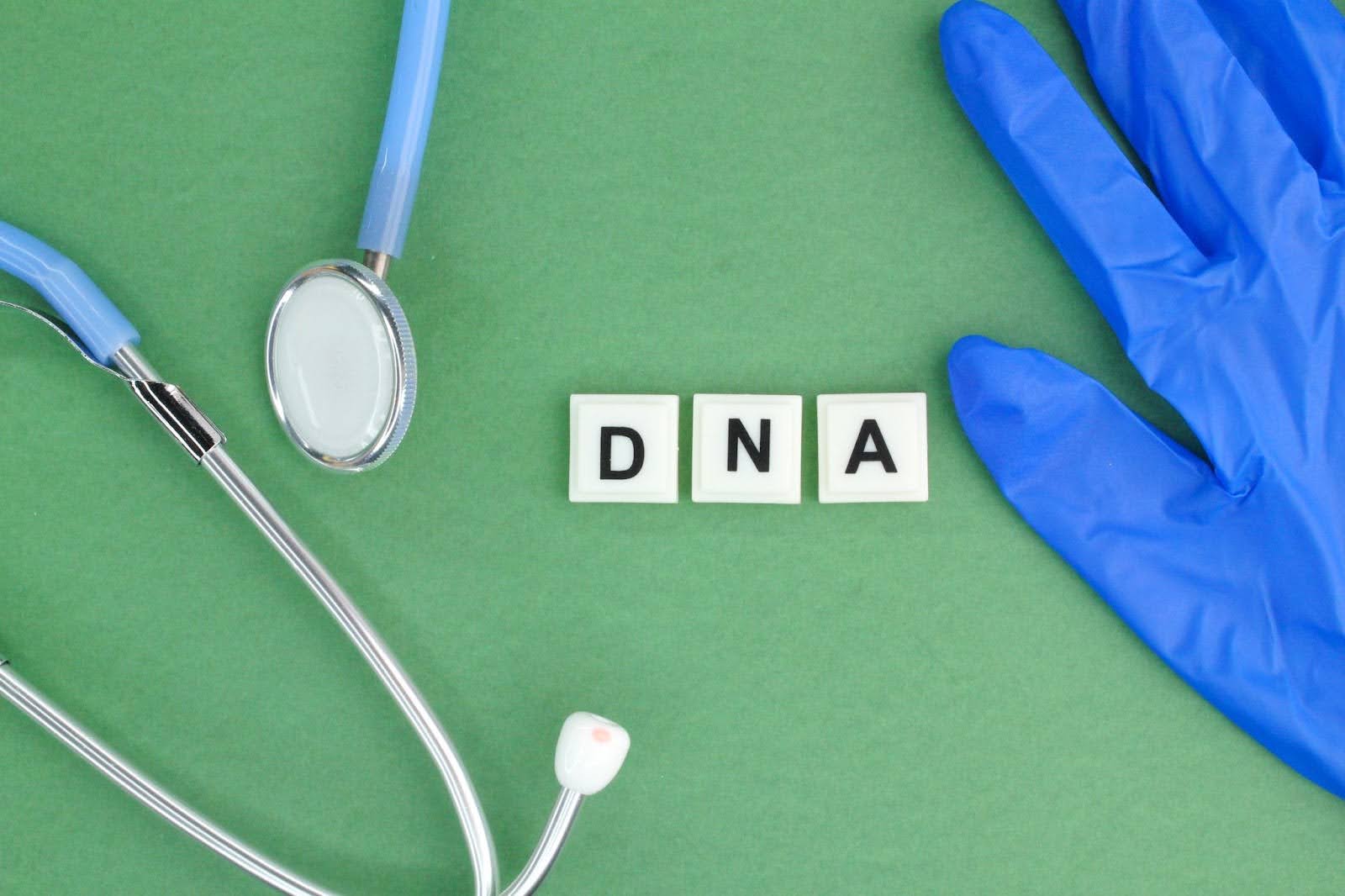 A stethoscope and protective gloves beside DNA letters representing genetic testing.